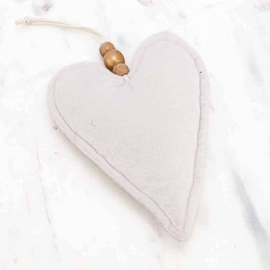 A cute little plush ornament in the shape of a white heart, adorned with a string hanger strung with wooden beads.