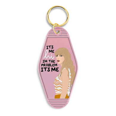 Pink keychain with drawing of Taylor Swift reads: It's me, hi, I'm the problem it's me