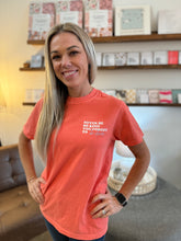 Load image into Gallery viewer, Model is wearing a short sleeve Custom Colors tee in coral with &quot;Never be so kind you forget to be clever&quot; on front corner.
