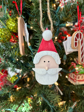  A wooden Santa Claus face ornament with a white pom pom on his hat. 