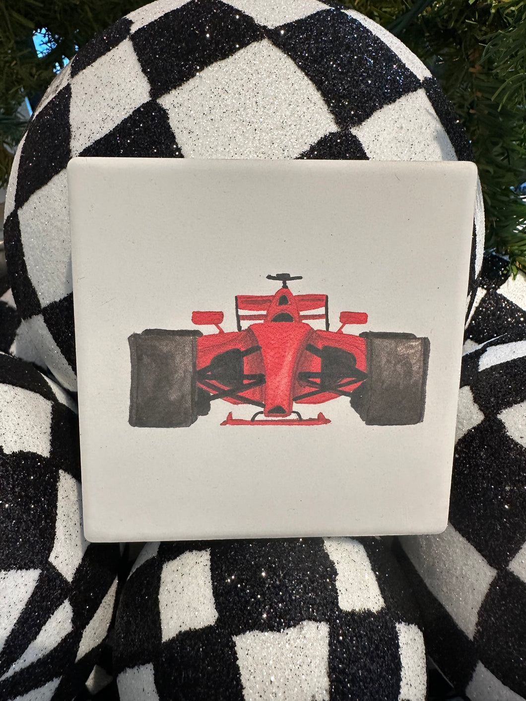 White ceramic coaster with a red race car painted on front. 