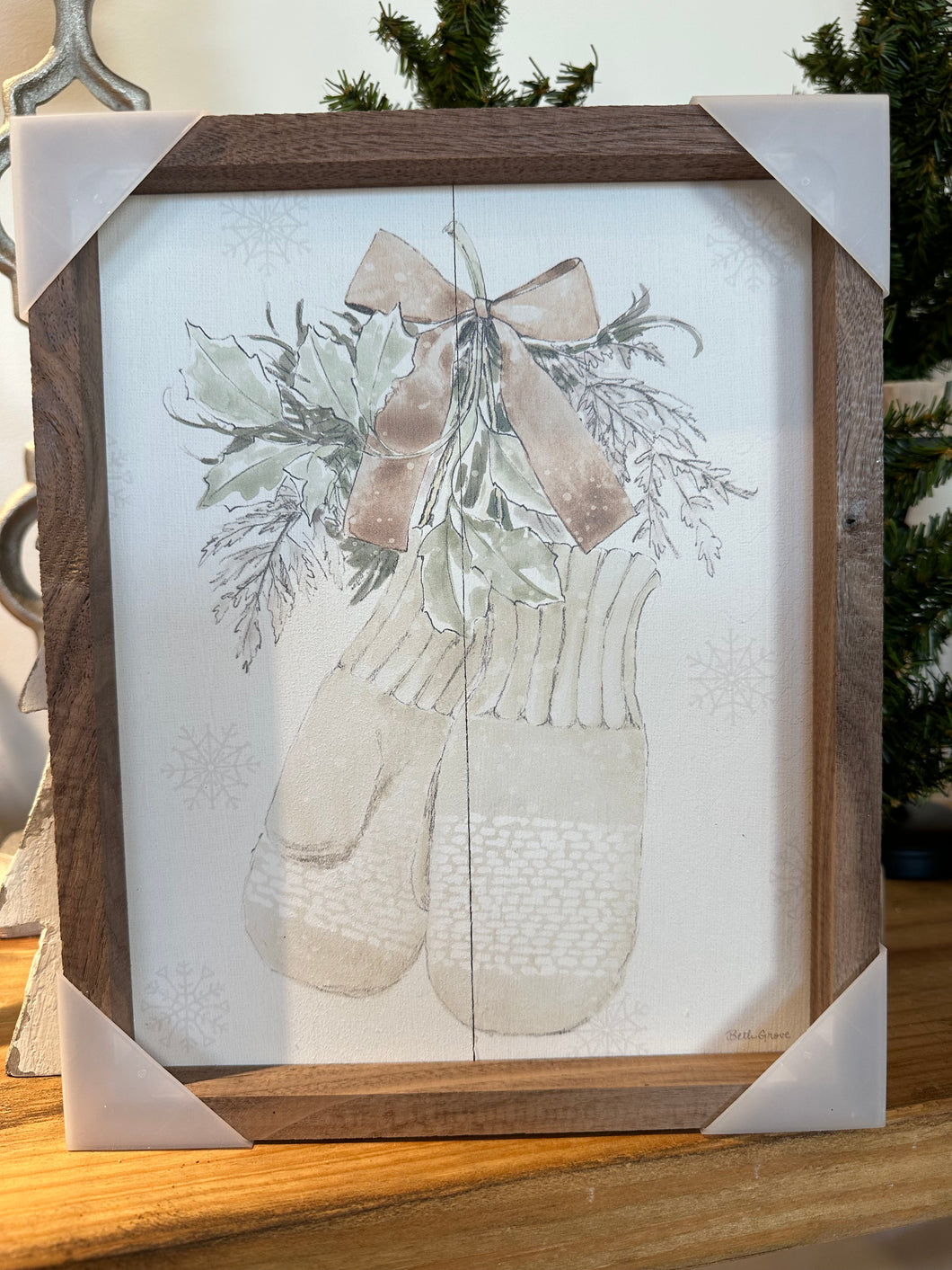 Wooden sign with white back ground, winter mittens, greenery, and a bow painted on front. 
