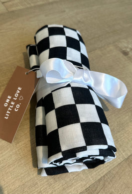 Black and white checkered blanket rolled up and tied with a white satin bow.  Made by One LIttle Love, Co. 