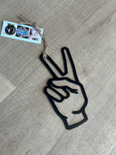 Load image into Gallery viewer, Black metal peace sign ornament.  Cutout hand showing 2 fingers up--a sign of peace.  Hung with twine. 
