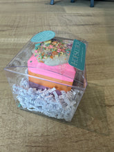 Load image into Gallery viewer, Rainbow surprise sidewalk chalk. Purple, orange, and hot pink layers with &quot;icing&quot; and &quot;sprinkles&quot; on top.  Resembles a piece of cake and packaged in a square clear plastic container. 
