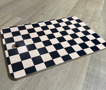 Load image into Gallery viewer, Black and cream checkered cutting board with hole to hang for display. 
