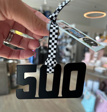 500 black metal ornament hanging from black and white checkered ribbon. 