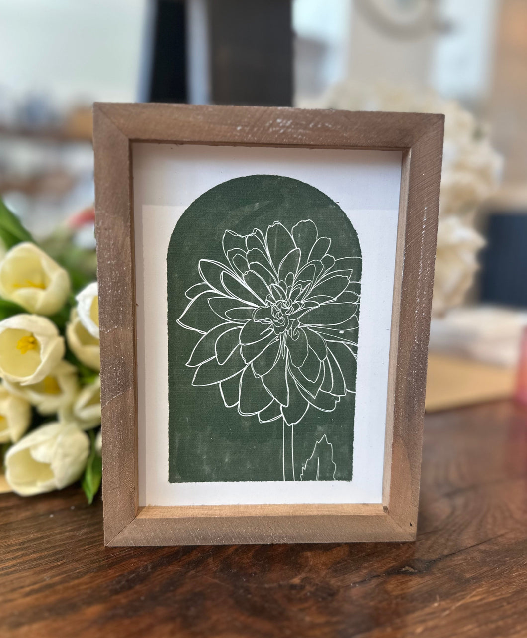 Framed wood sign with white inside frame, green background, and white ink chrysanthemum. 