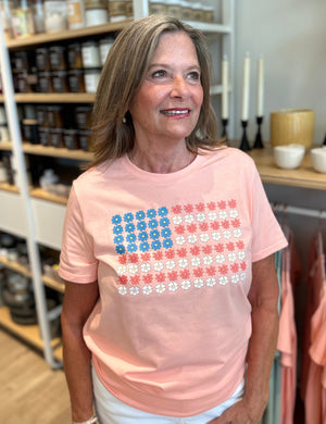Peach tee shirt with American flag in floweres on front. 