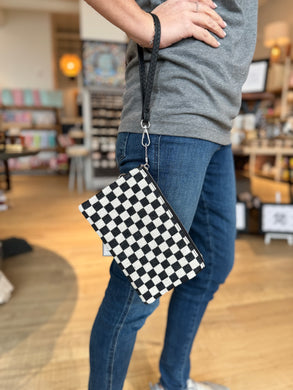 Black and white checkered crossbody/wristlet.  Model is shown using as wristlet. 