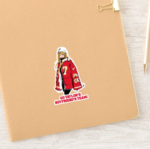 Load image into Gallery viewer, Taylor Swift &quot;Go Taylor&#39;s Boyfriend&#39;s Team!&quot; sticker shown on a notebook.  
