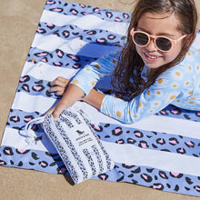 Load image into Gallery viewer, LIttle girl laying on the Kids Quick Dry Towel and holding the pouch it comes in for size reference. 
