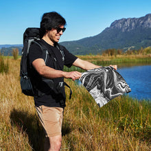 Load image into Gallery viewer, Man in the mountains holding the Quick Cooling towel (27X13) for size reference.  
