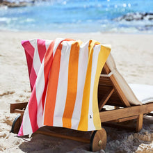 Load image into Gallery viewer, Peach Sunrise Dock &amp; Bay Quick Dry Towel is shown hanging on the back of a beach chair. 
