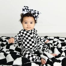 Load image into Gallery viewer, Little girl with checkered zipper onesie and checkered bow in her hair sitting on a checkered blanket. 
