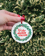 Load image into Gallery viewer, white ornament with &quot;tis the damn season&quot; in red in center inside a wreath
