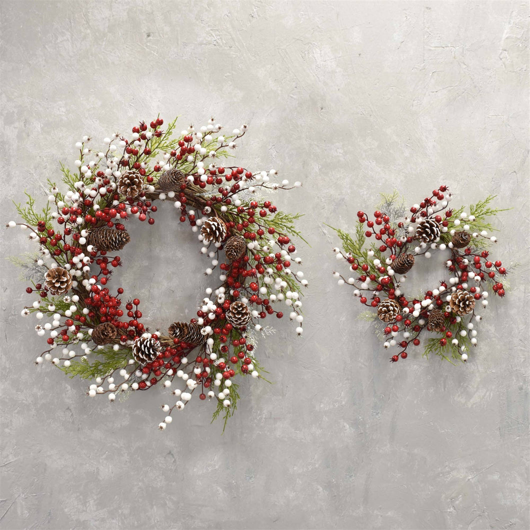 2 sizes of cedar pine cone wreaths with white and red berries and some pine greenery 