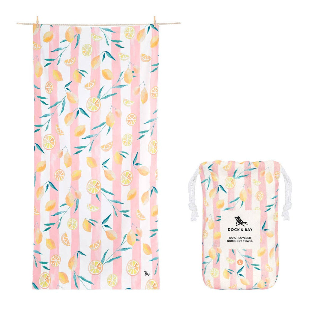 Dock & Bay Quick Dry Extra Large Towel in the color Lemons.  It is light pink and white striped with whole and slices lemons and thin green leaves all over.  Also shown is a the carrying pouch that comes with it in the same pattern. 