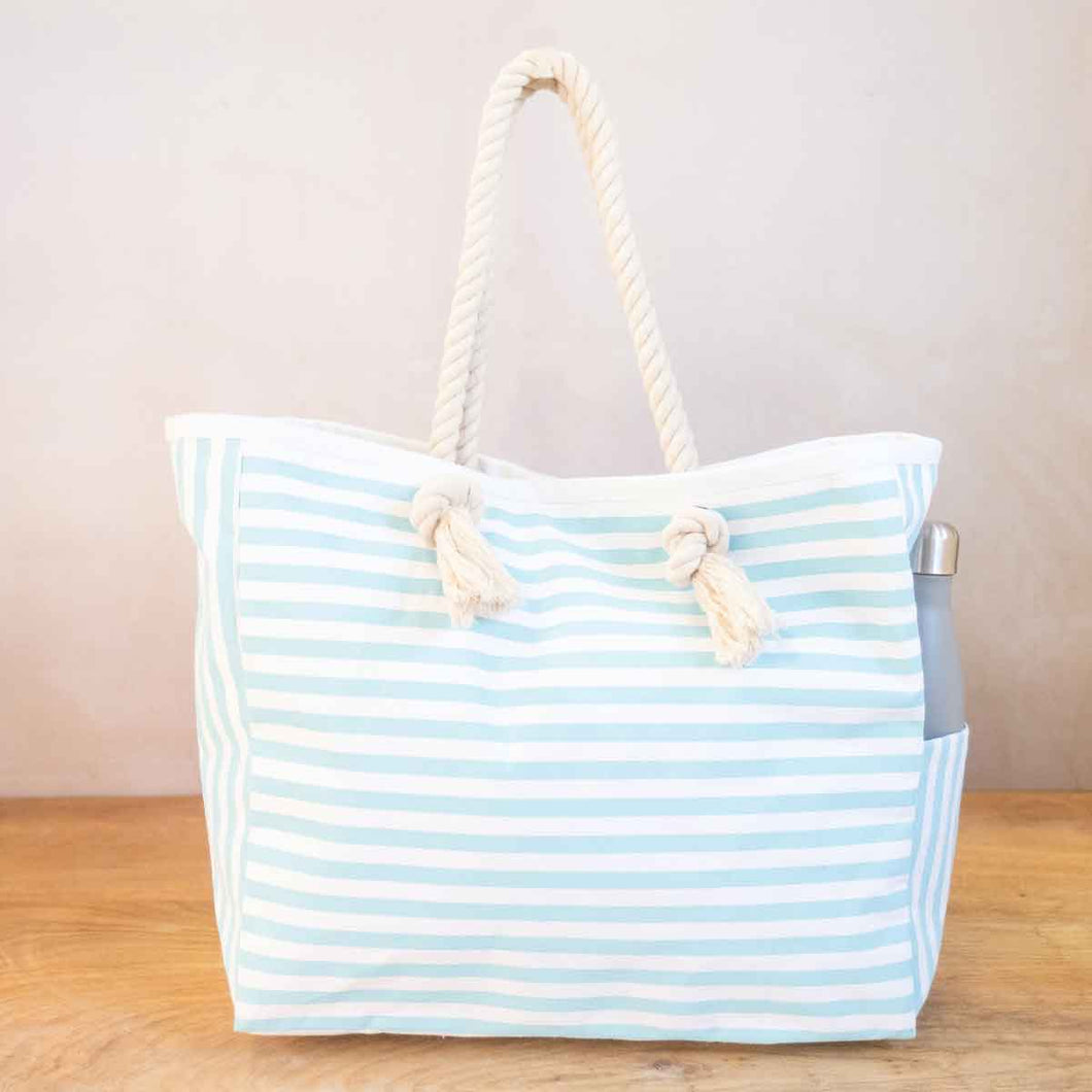 Canvas beach tote with Aruba blue and white horizontal stripes and rope straps.  Has an interior pocket and magnetic closure.  Also has a pocket on the outside on one side. 15X14X6 