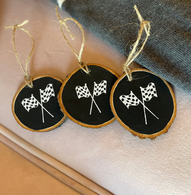 Shows 3 handpainted woodslice ornaments.  Handpainted black with 2 crossing checkered flags on each one.  Twine hanger.  Approx 3x3. 